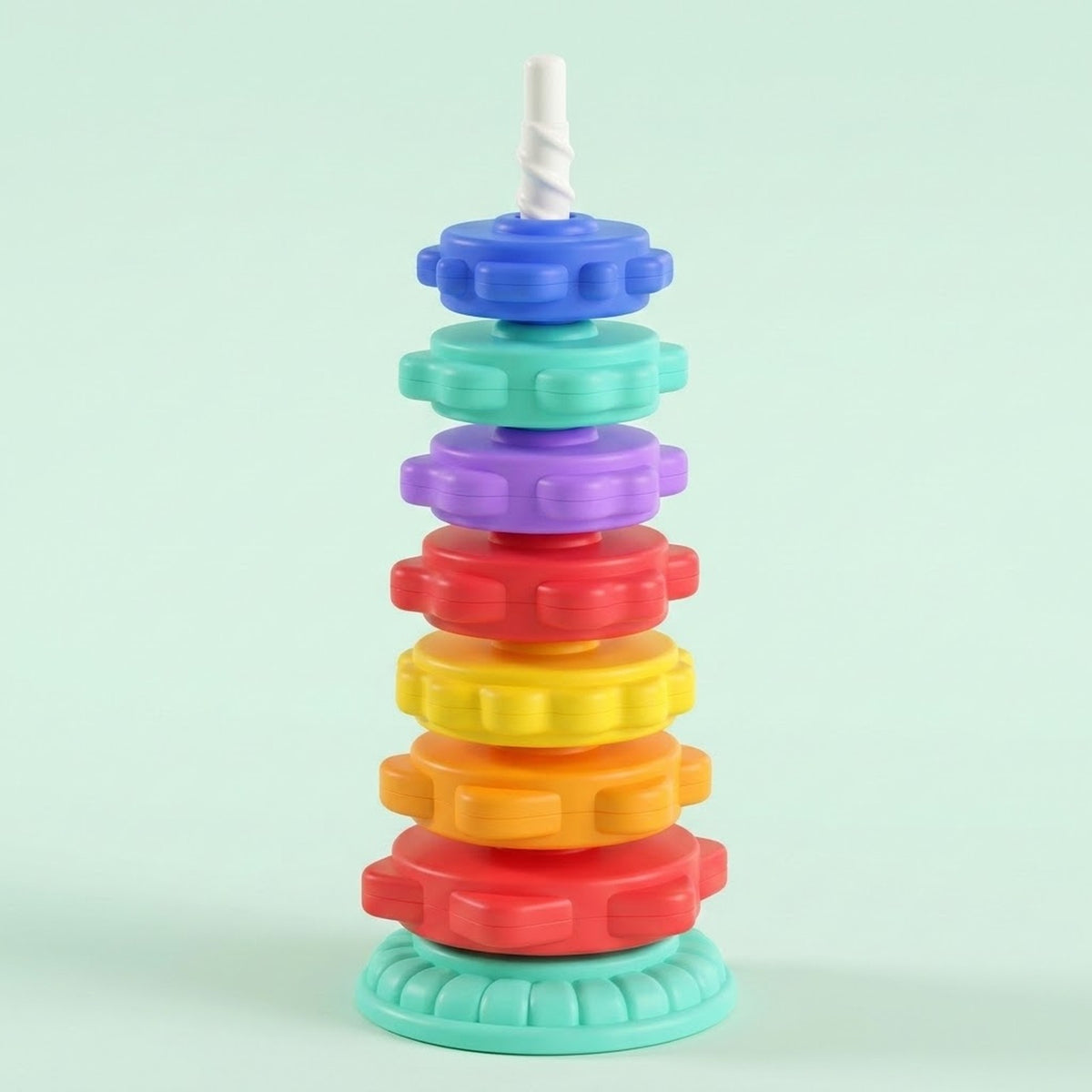 A stacking toy with seven colourful gear-shaped rings, a white spiral post and mint base stands against a pale mint background.