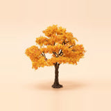 A model tree with spreading orange foliage, exposed dark branches, and a brown trunk stands against a pale peach background.