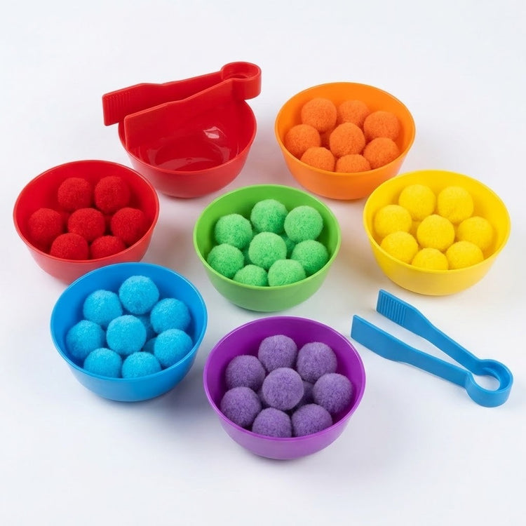 Sorting toy set on white with color-matched pom-poms in rainbow plastic bowls, an extra empty red bowl, and two tweezers.