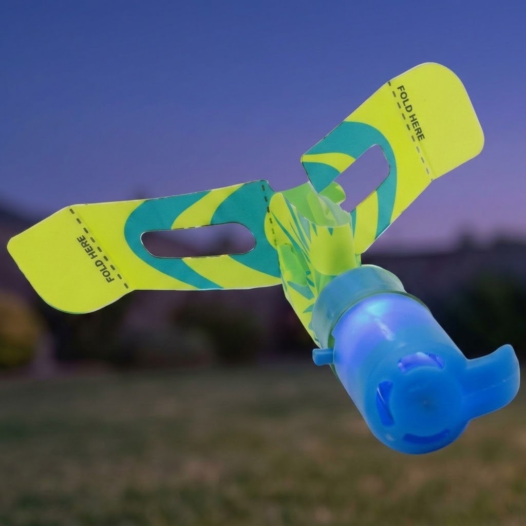 A blue slingshot helicopter glows against a dusk sky, with yellow and teal rotor blades marked FOLD HERE.