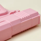 A close-up shows the pink plastic water gun’s ribbed body and molded seams against a light cream background.