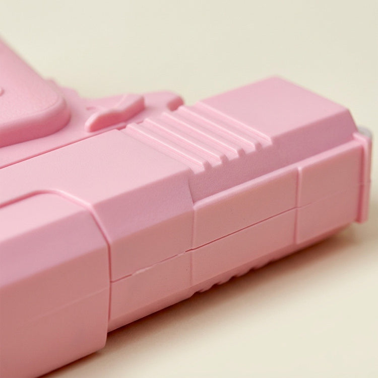 A close-up shows the pink plastic water gun’s ribbed body and molded seams against a light cream background.