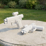 Two white plastic water guns rest on a round stone garden table, one standing upright and the other lying flat.