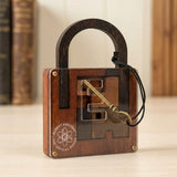 Brown wooden lock puzzle stands on a pale tabletop with its brass-coloured key across the clear front and blurred books behind.