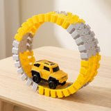 Yellow and gray car track set formed into an upright circular loop with a yellow mini car on a light wooden table.