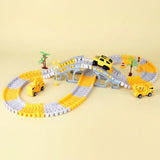A children's toy construction-themed race track set with yellow and gray interlocking blocks forming an oval track, a small gray bridge, miniature palm trees, and three yellow toy vehicles including a car and two construction trucks, photographed on a plain beige background.
