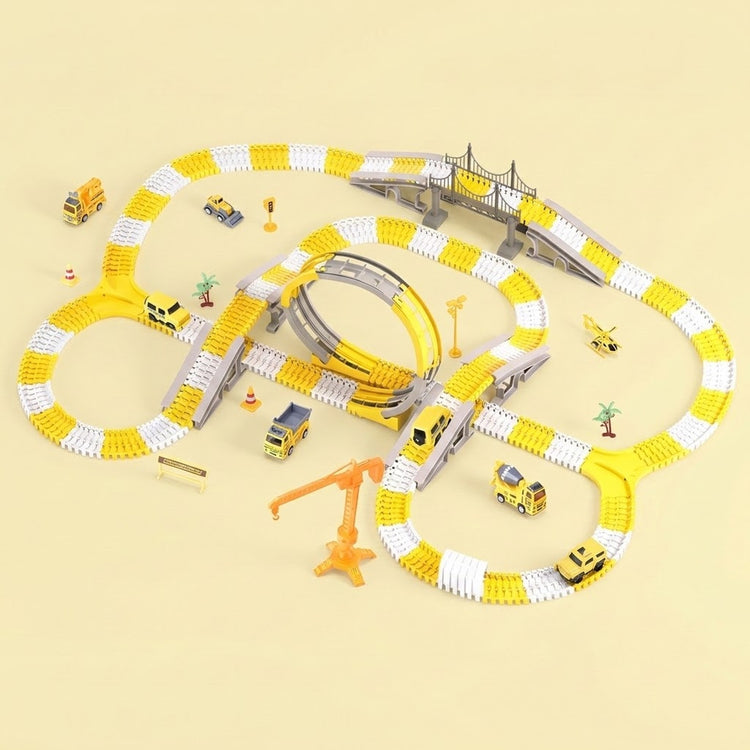 A children's toy train track set arranged on a pale beige background. The set includes a yellow and white looped track, a curved track section, a bridge, an orange crane, small toy cars, and tiny construction-themed accessories.