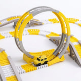 A yellow and gray plastic toy train track set with a small yellow car, photographed on a clean white background.