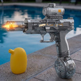 A gray electric water gun displays an orange flame effect beside a yellow container on a stone pool edge.