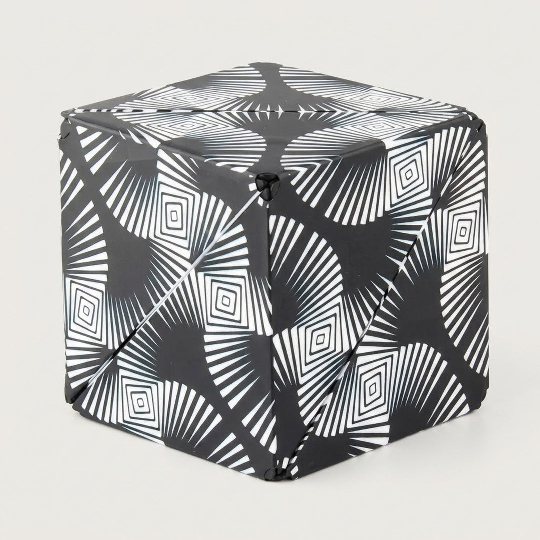 Black and white puzzle cube with radiating lines and nested diamond patterns shown folded closed against a light grey background.
