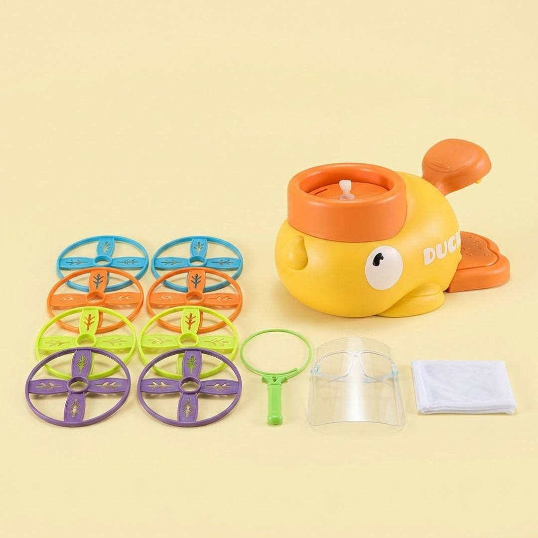 A yellow duck-shaped disc launcher with orange pedals accompanies eight colorful discs, net components, and a clear face shield against a pale yellow background.