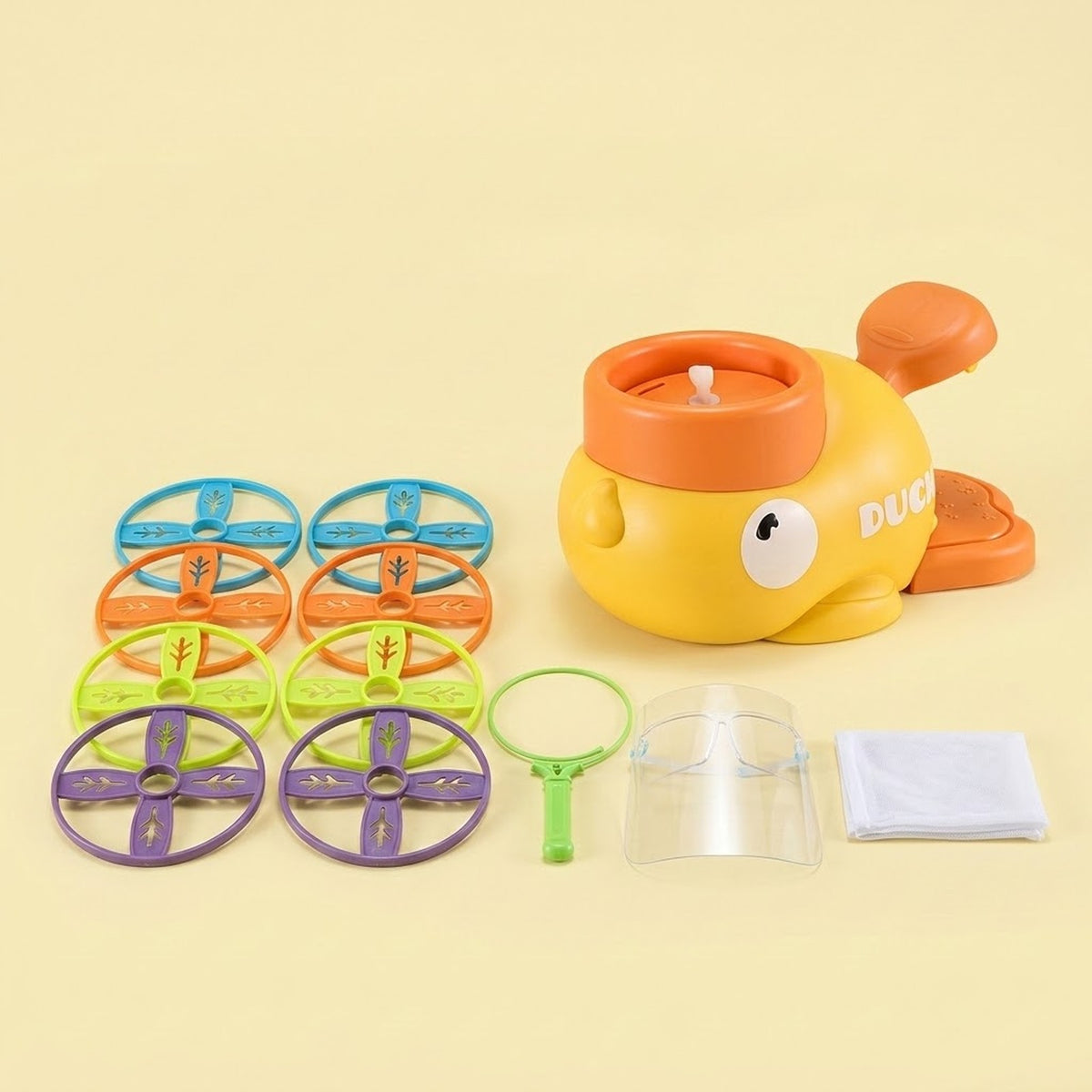 A yellow duck-shaped disc launcher with orange pedals accompanies eight colorful discs, net components, and a clear face shield against a pale yellow background.