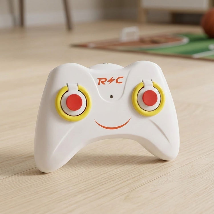 The remote control helicopter's white controller has red buttons, yellow trim, and a smiling face design on a light wooden floor.