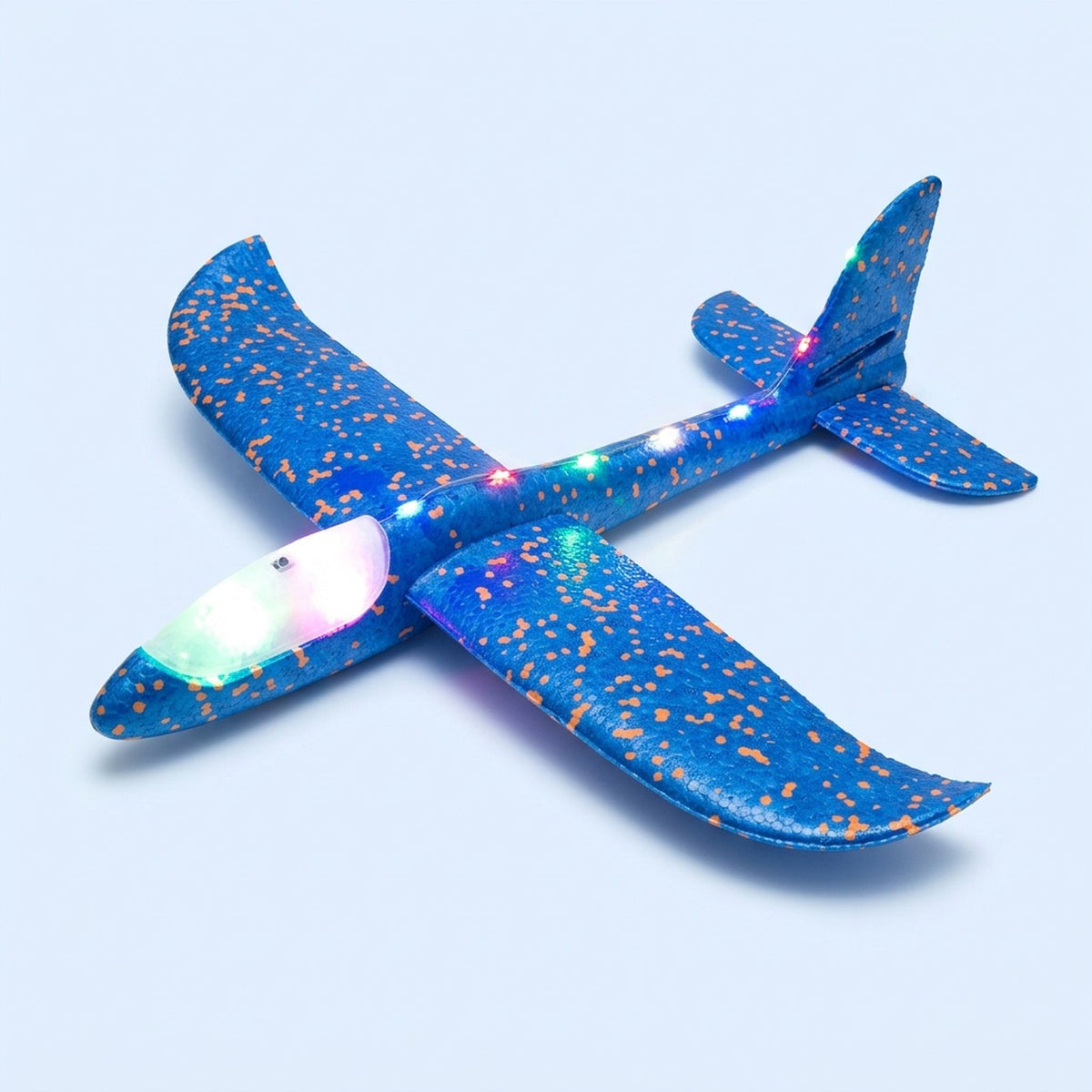 Blue foam toy glider with orange speckles, glowing multicoloured LEDs and an illuminated canopy rests on a light blue background.