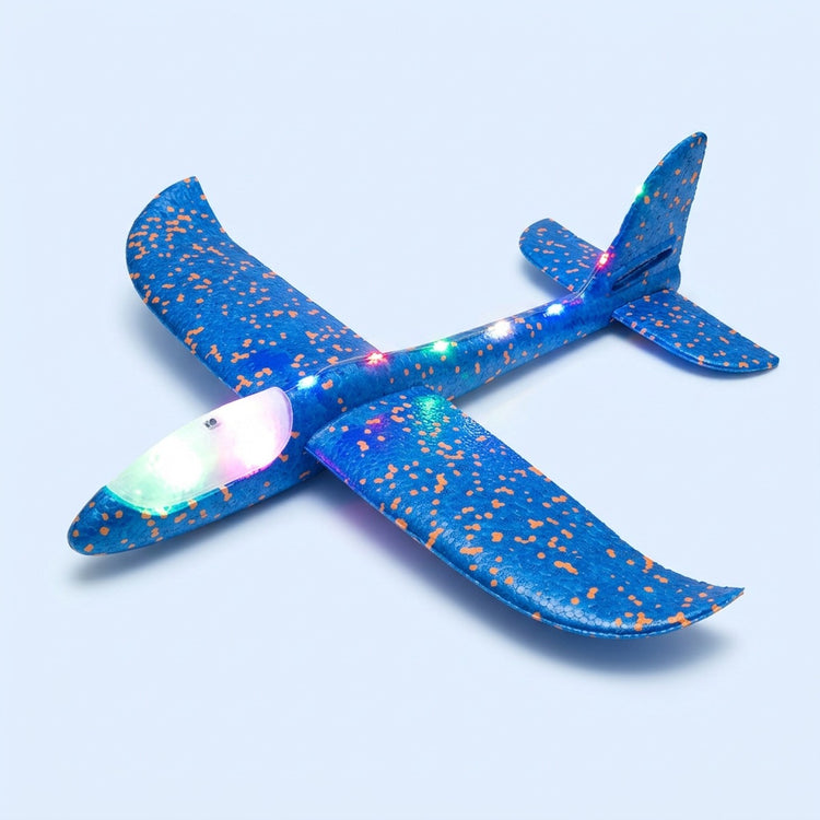 Blue foam toy glider with orange speckles, glowing multicoloured LEDs and an illuminated canopy rests on a light blue background.