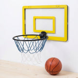 A wall-mounted mini basketball hoop set with a bright yellow backboard frame, black rim, blue net, and white net, shown on a light wall above a wooden surface with a small orange basketball nearby.