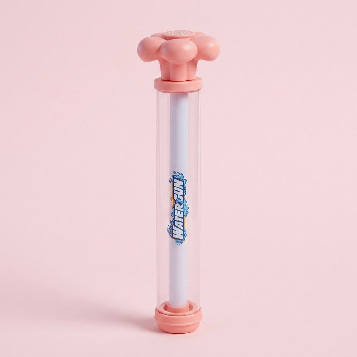 A pink and clear water gun with a white inner tube and flower-shaped handle stands upright against a pale pink background.