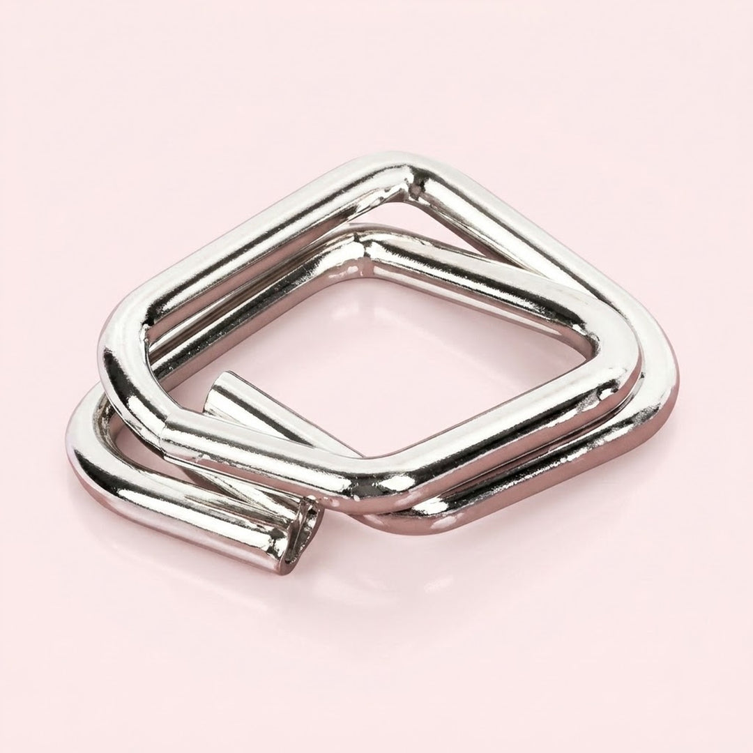 Silver metal square puzzle from the brain teaser set, with interlocking open wire shapes on a pale pink background.