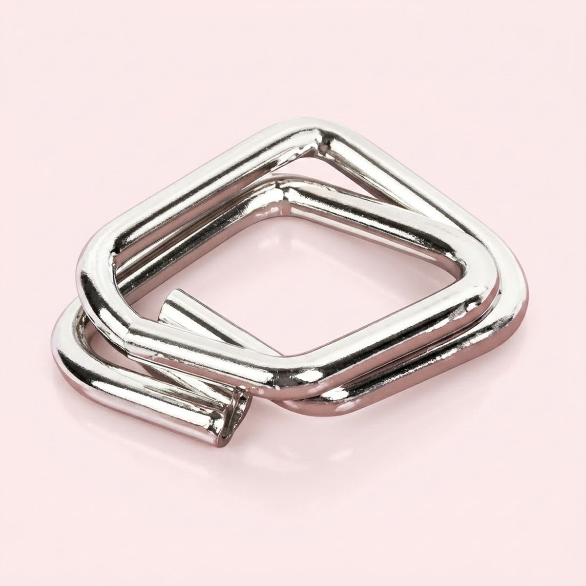 Silver metal square puzzle from the brain teaser set, with interlocking open wire shapes on a pale pink background.