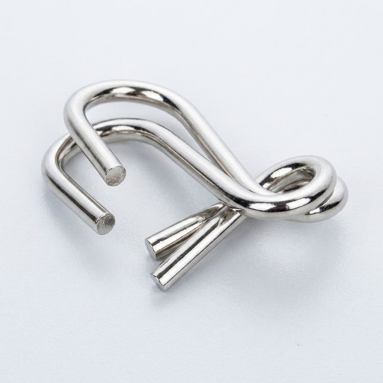 Close-up of a silver-colored interlocking curved wire puzzle from the brain teaser set against a white background.