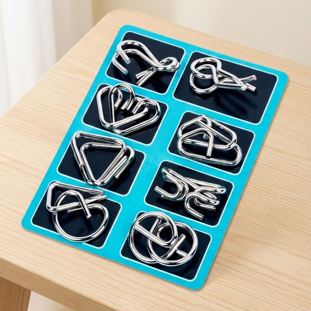 Eight-piece silver metal wire brain teaser set arranged on black panels with turquoise borders on a light wooden table.