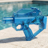 A translucent blue electric water gun with an angular body sprays water from pale stone coping beside a swimming pool.
