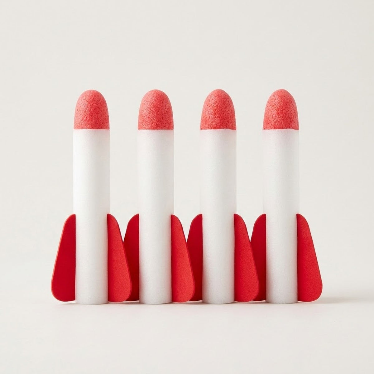 Four white rockets for a rocket launcher toy stand upright with red tips and fins against an off-white background.