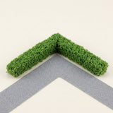 Two green miniature hedge strips form a right-angle corner beside a gray model path on a cream background.