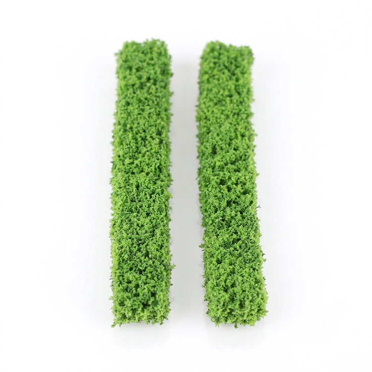 Two green model hedges with textured foliage lie parallel on a plain white background.