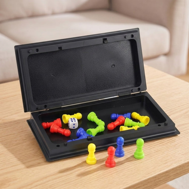 An open black plastic ludo set holds colourful pawns and a white die on a light wood table beside a beige sofa.