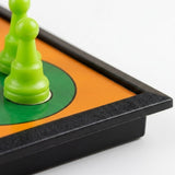 A close-up of the ludo set shows bright green plastic pawns on an orange and green board with a black border.
