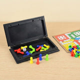 Ludo game set with an open black plastic storage case holding colorful pieces and a die, folded board beside it on a light wood surface.
