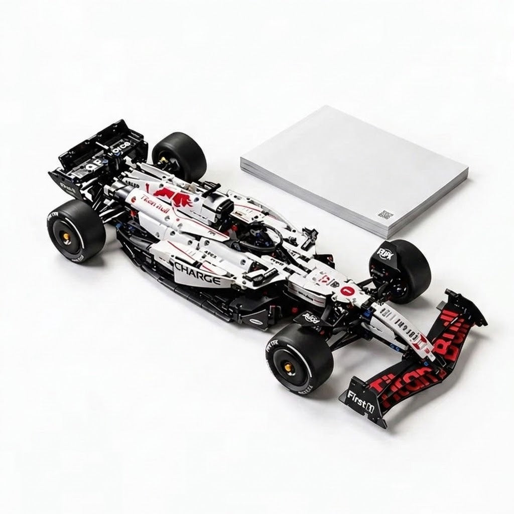 Assembled white and black car building set with red accents sits beside a closed gray booklet on a white background.