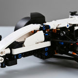 Close-up of the car building set shows white plastic panels, black framework, and blue connectors against a gray background.