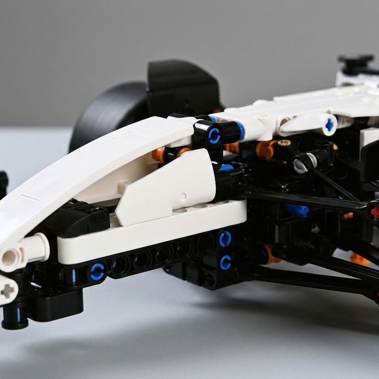 Close-up of the car building set shows white plastic panels, black framework, and blue connectors against a gray background.