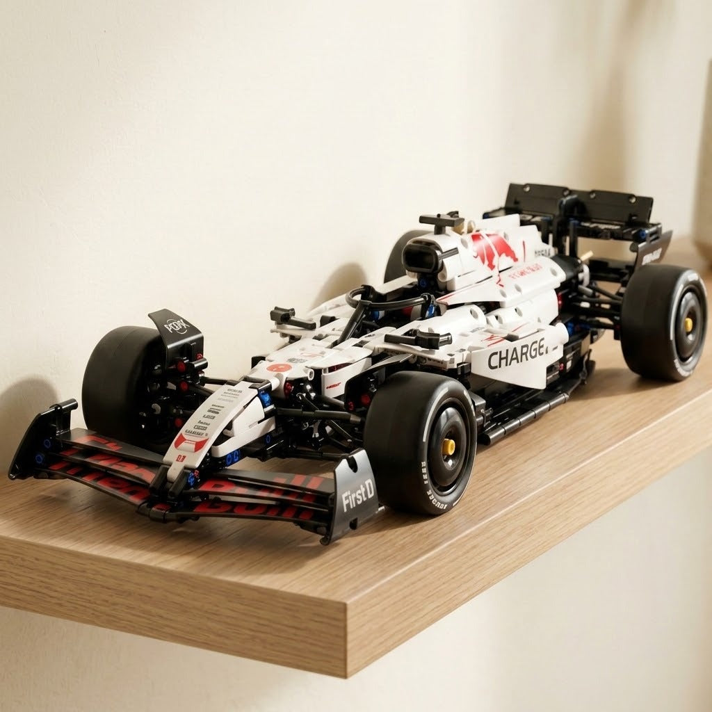 White and black building-block race car with red accents rests on a light wooden floating shelf against a cream wall.