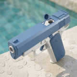 A blue and white water gun with an open filling cap stands on wet stone beside a swimming pool.