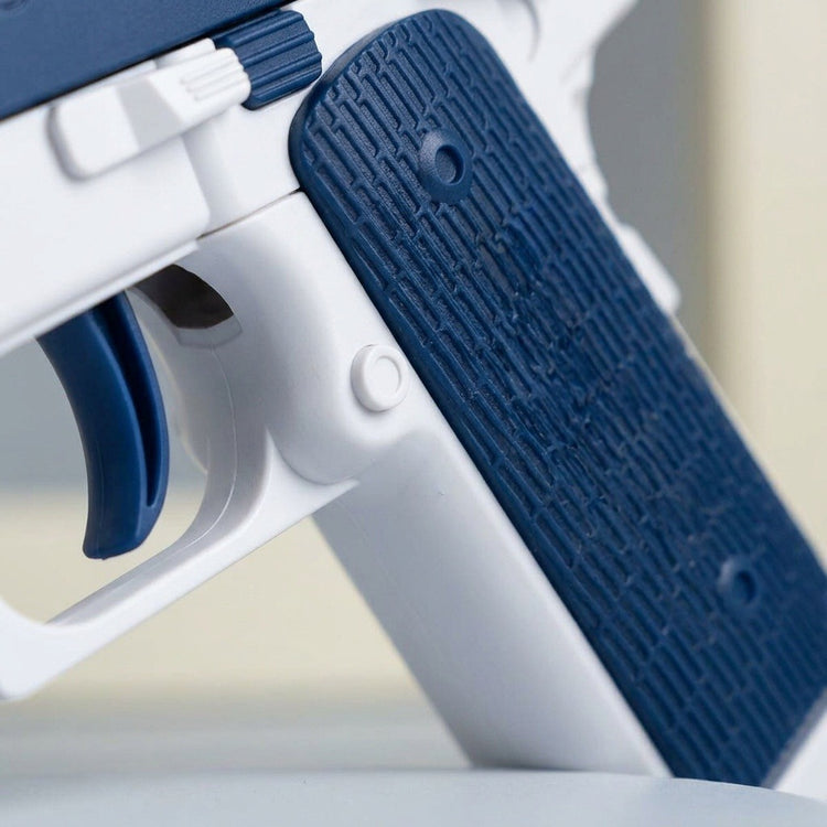 A close-up shows the blue and white water gun's textured grip and curved blue trigger against a blurred pale background.