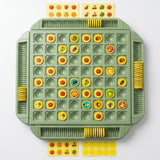 A green memory matching game viewed from above shows yellow fruit pieces, grooved storage trays, and sticker sheets on white.