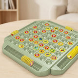 Green memory matching game with yellow fruit tokens and grooved side trays on a pale wooden table beside a cream sofa.