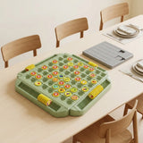 Green memory matching game with yellow tokens beside a gray rectangular accessory on a dining table set with plates and cutlery.