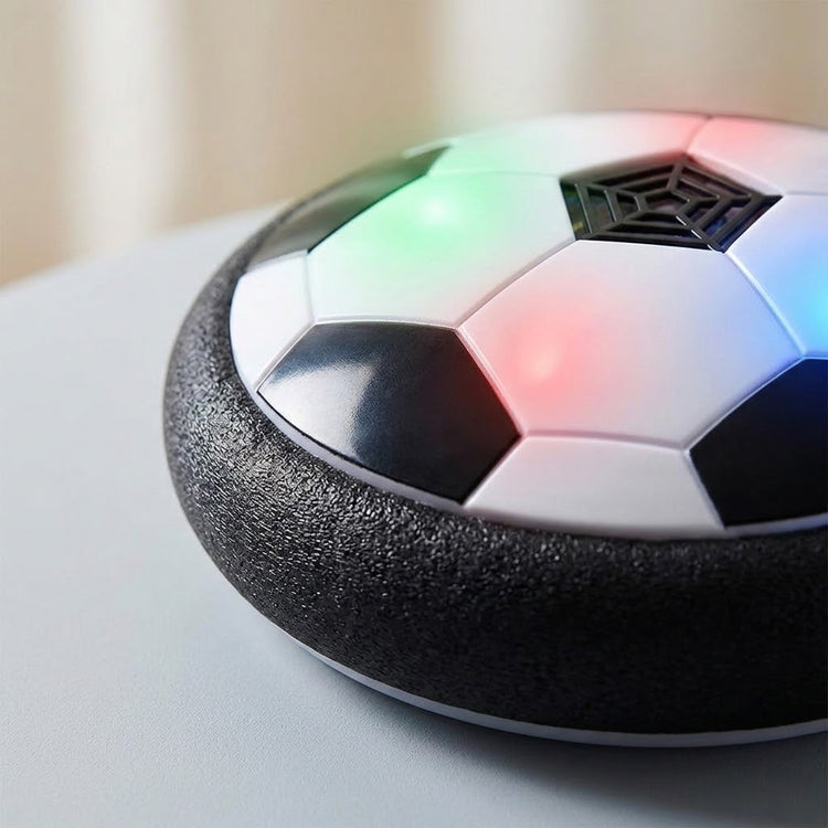 A close-up shows the hover soccer ball's textured black foam bumper, glossy black and white panels, and colored lights on a pale surface.