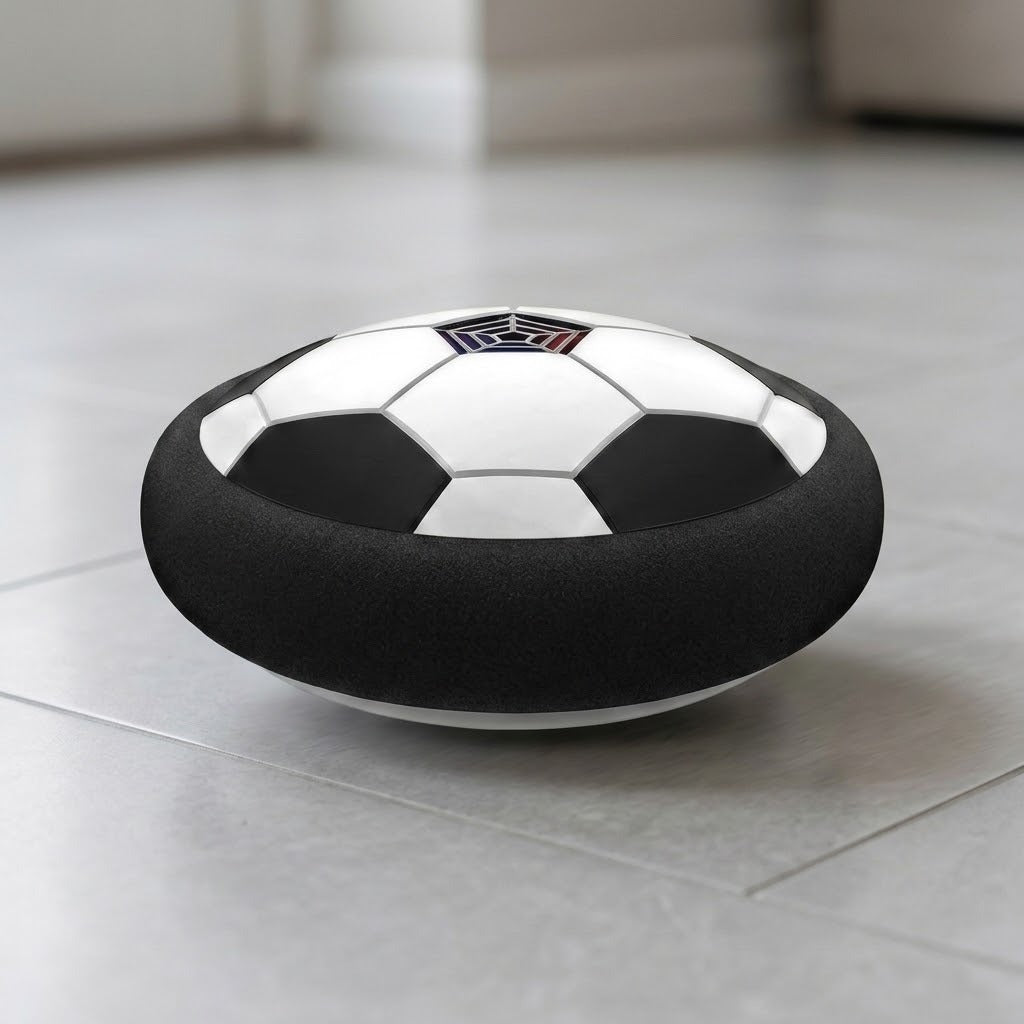 Black-and-white hover soccer ball with a thick black foam bumper viewed at floor level on light gray indoor tiles.