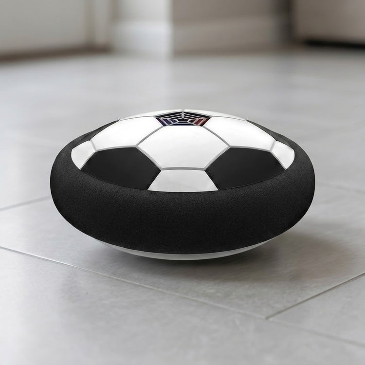 Black-and-white hover soccer ball with a thick black foam bumper viewed at floor level on light gray indoor tiles.