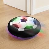 Black-and-white hover soccer ball with colorful LEDs and a black foam bumper on a pale wooden floor beside an open doorway.