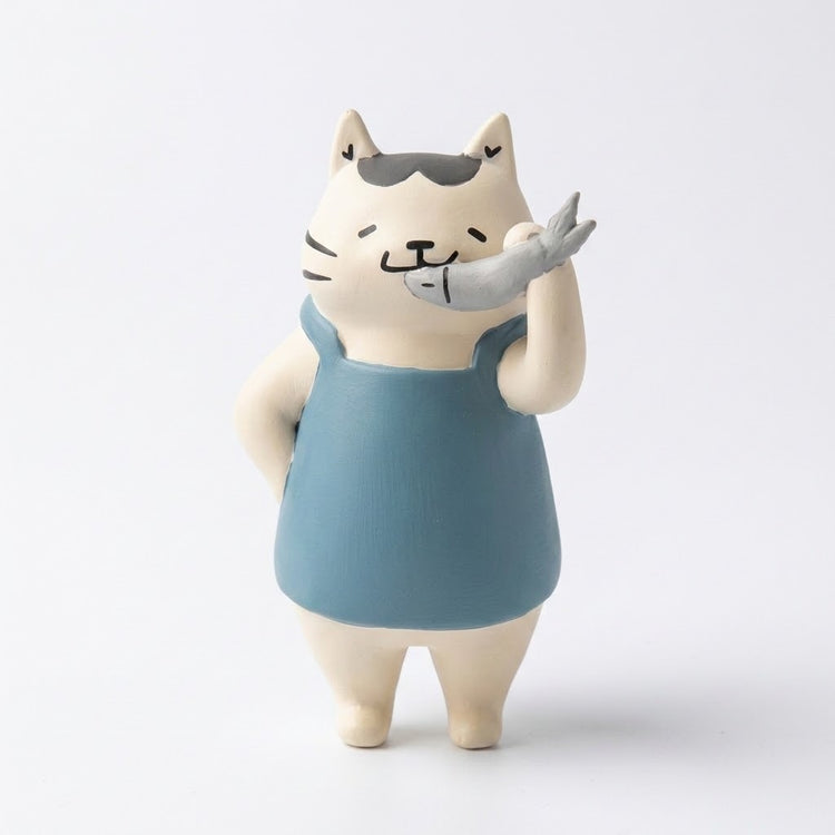 A cream cat blind box figure wears a blue apron and holds a gray fish near its mouth against a white background.
