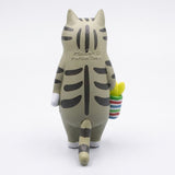 The gray tabby cat blind box figure shows its striped back, long tail, and basket from behind against a white background.