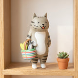 Gray tabby cat blind box figure holds a multicolored striped basket on a wooden shelf beside a small potted succulent.