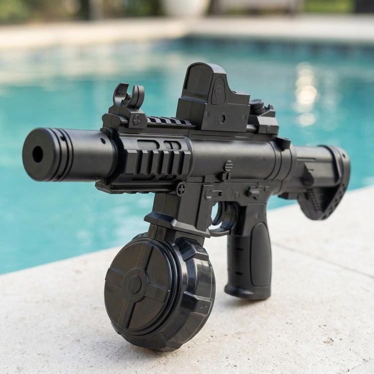 A black electric water gun with a cylindrical barrel, top sight and drum reservoir stands on pale paving beside turquoise pool water.