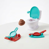 Tabletop game on a white background with a turquoise-lidded white toilet, two red and turquoise launchers, and a brown toy poop airborne.